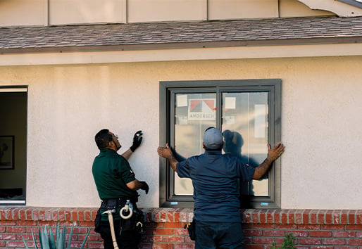 Two contractors install a flush fin window in a stucco home. 