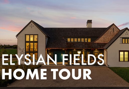 A roof punctuated by four dormer windows peeks over the brow of a hill covered in prairie grass at golden hour.