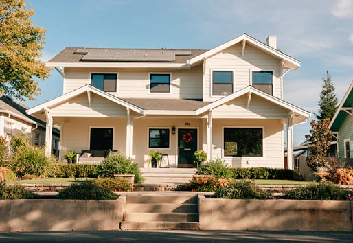 A white home with black replacement windows and solar panels on the roof.