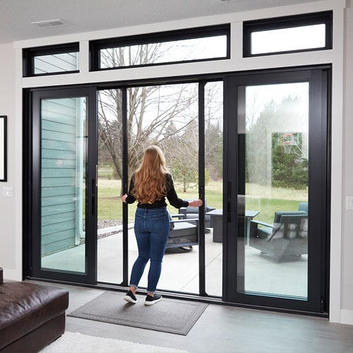 woman walking out to patio with black framed andersen sliding door